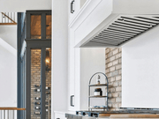 Side view of the 30 Inch 750 CFM Range Hood Insert installed in a white custom cabinet hood above a gas range