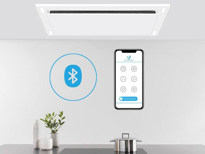 Matte white wireless flush ceiling mount range hood installed above kitchen island with smartphone control