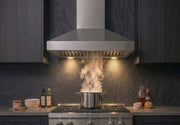 Victory Twister wall mount range hood installed between dark cabinets above a gas range, capturing steam from a cooking pot with LED lights on